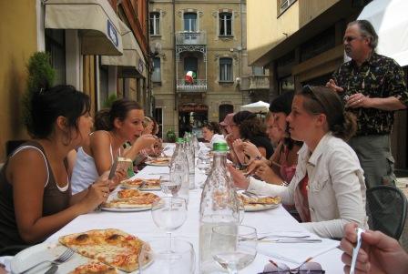 Group of people eating pasta around a long table